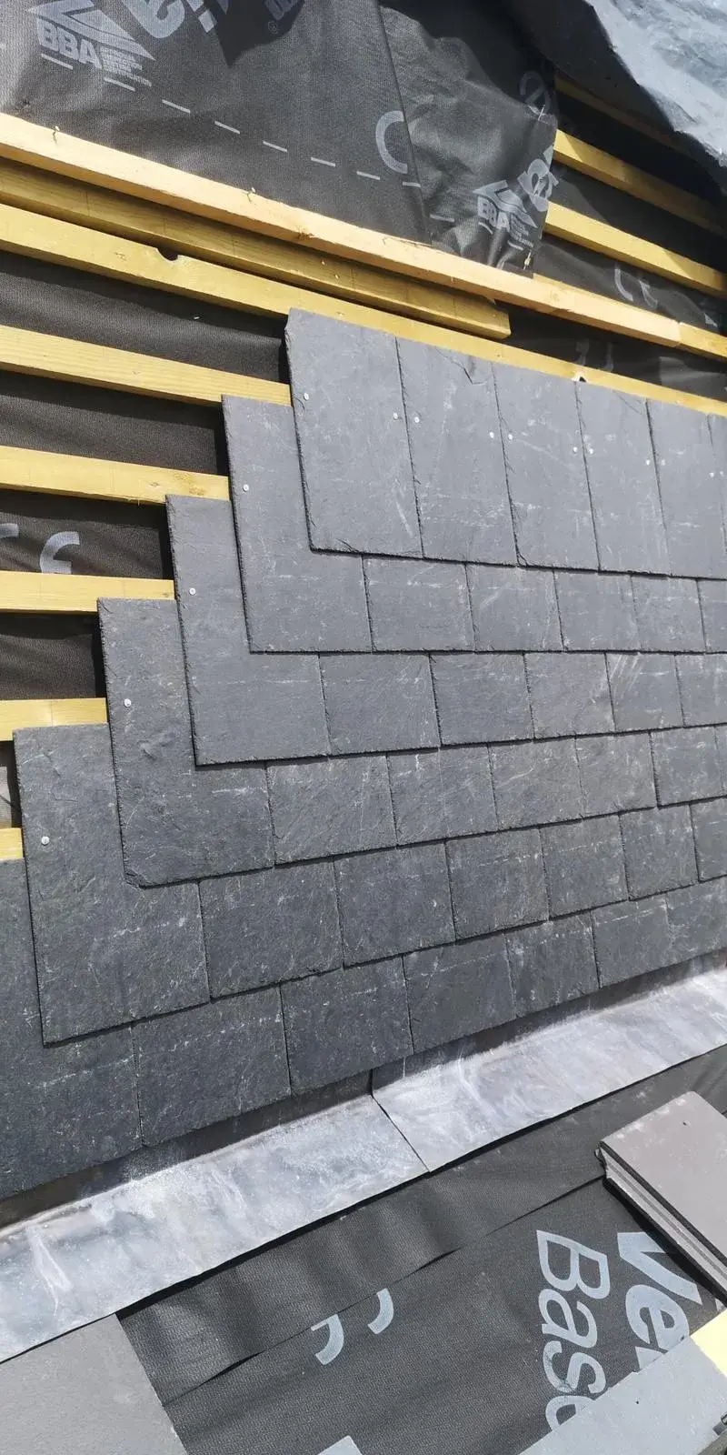 a pile of black bricks sitting on top of a wooden floor