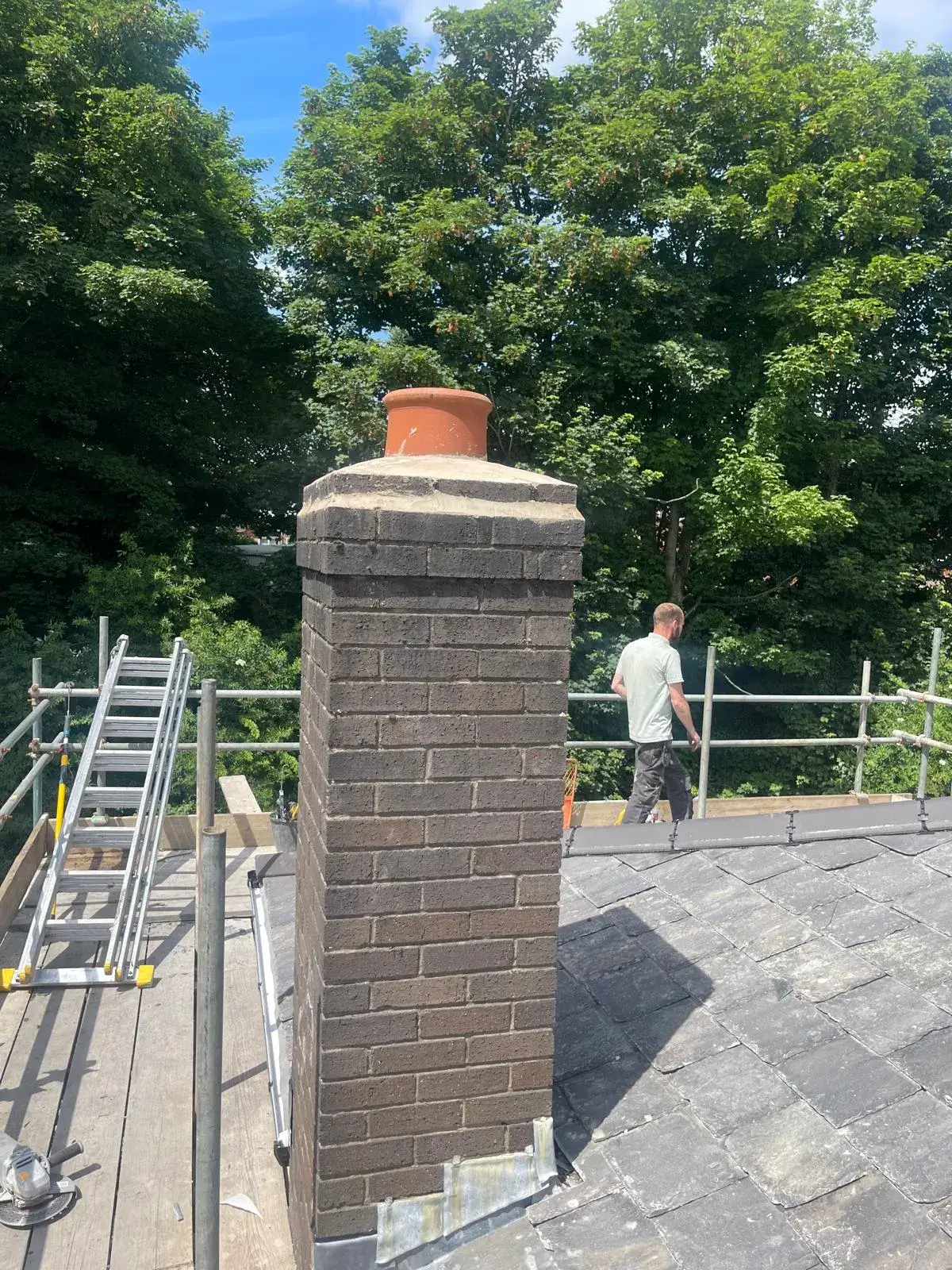 a man standing on a roof next to a brick chimney